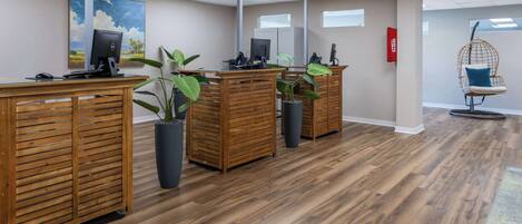 A reception area with wooden desks, potted plants, a hanging chair, and a painting on the wall.