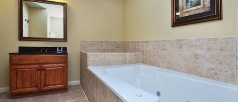 A bathroom with a bathtub, wooden vanity, and a framed picture on the wall.