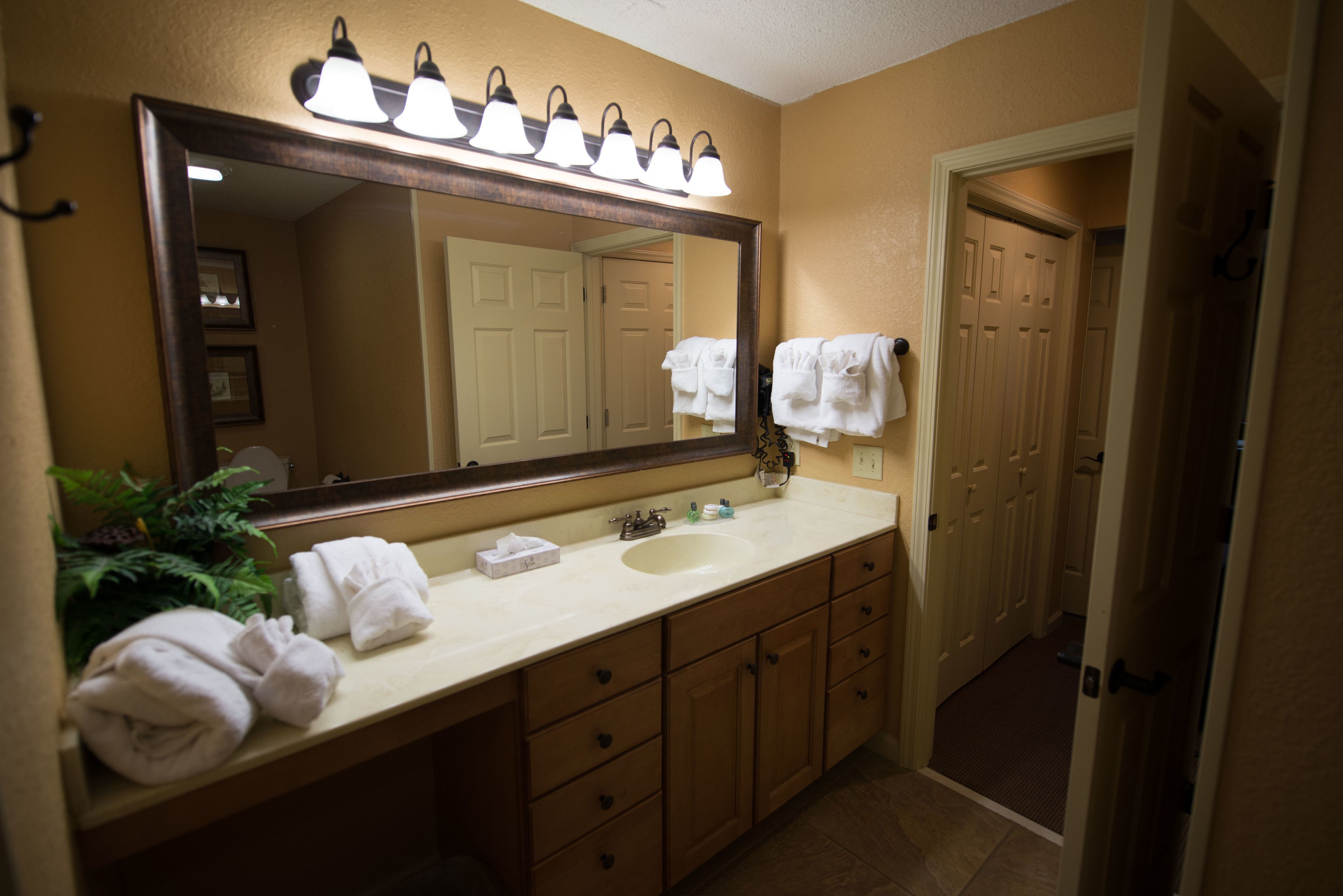 Une salle de bain avec un grand miroir, un lavabo et un porte-serviettes.
