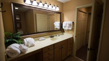A bathroom with a large mirror, a sink, and a towel rack.
