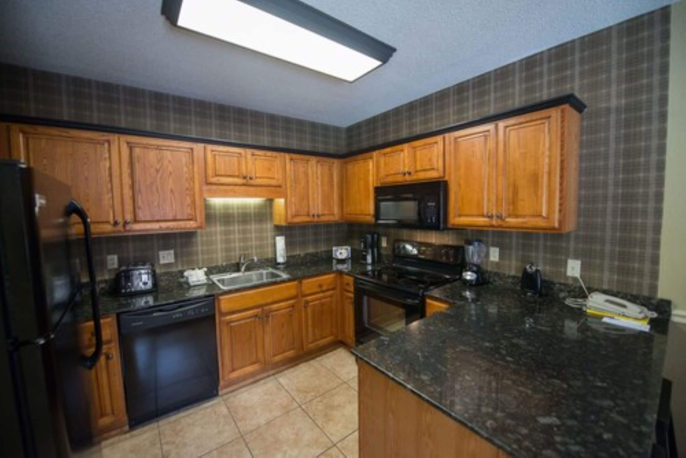 A kitchen with wooden cabinets, a black refrigerator, a microwave, and a dishwasher.