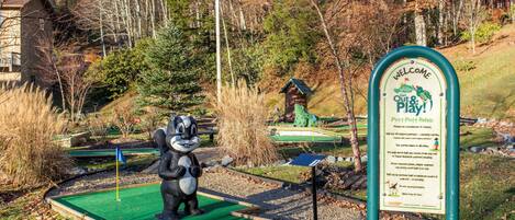 A miniature golf course with a signboard and a mascot.