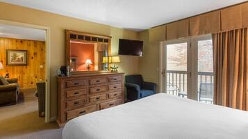 A hotel room with a large bed, wooden dresser, two lamps, a TV, and a balcony with curtains.