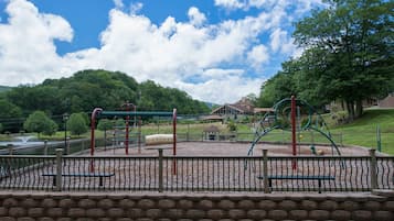 Children can play on swings, a slide, and climbing structures in this secure playground area.