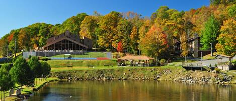 Ein See mit Blick auf ein Pavillon, ein Gebäude mit geneigtem Dach und Herbstbäume.