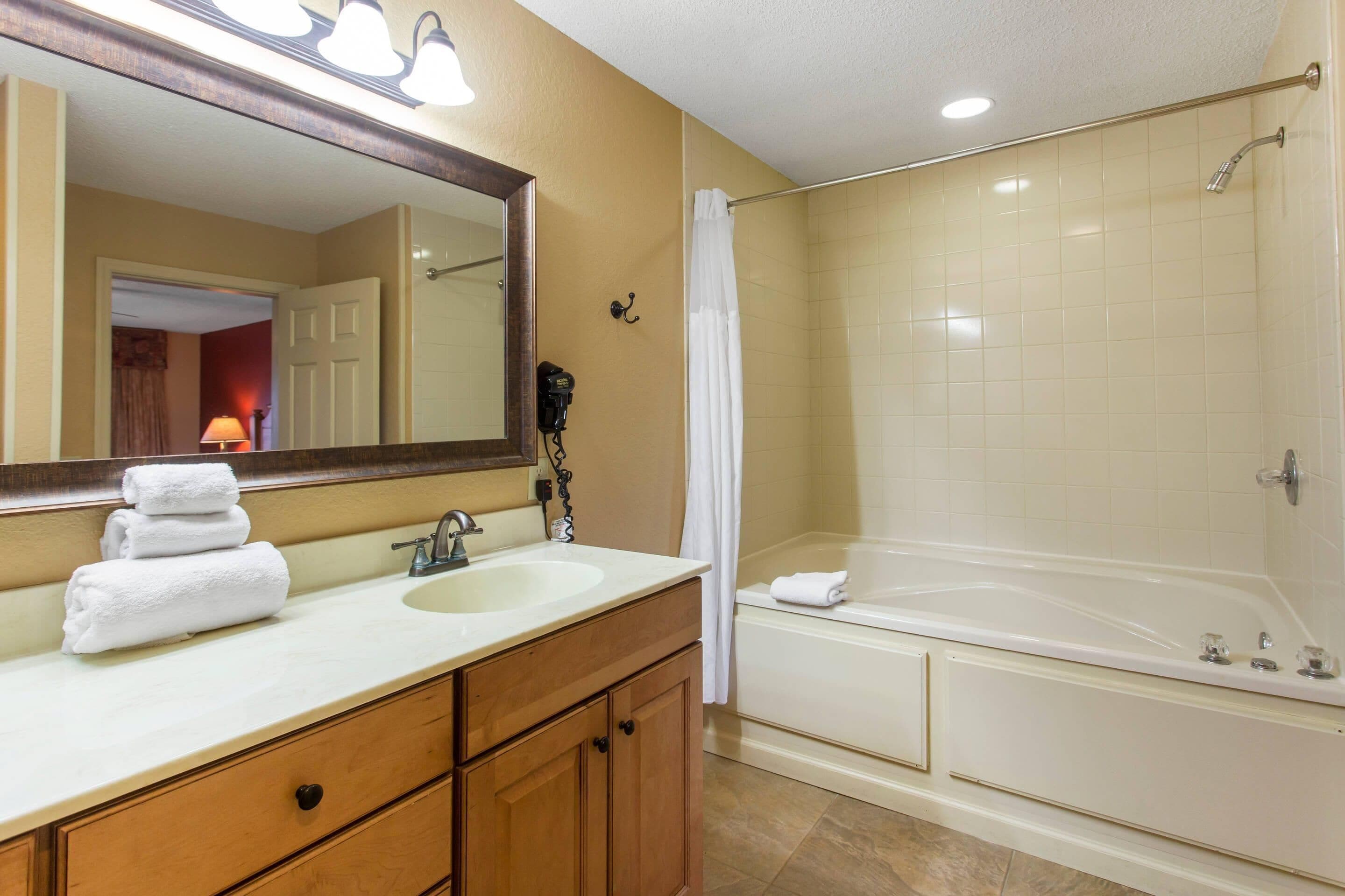 A bathroom with a sink, mirror, and bathtub.