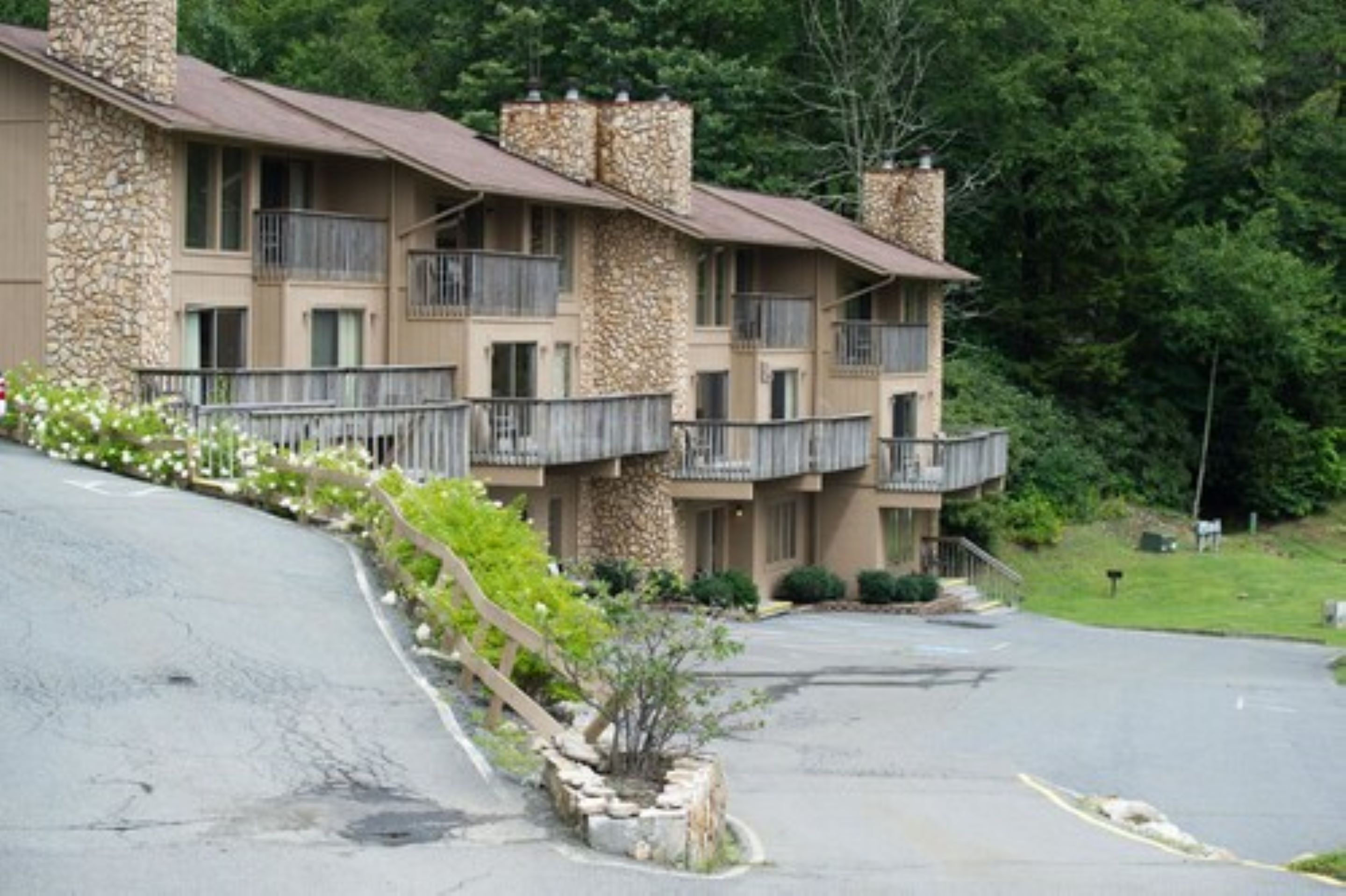 Un hotel de varios pisos con fachadas de piedra, balcones y un estacionamiento.