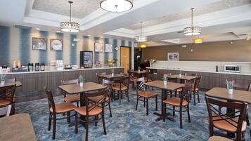 A hotel lobby with a reception desk, seating area, and a kitchen.