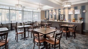 Un comedor de hotel con varias mesas y sillas, un bar y decoración en las paredes.