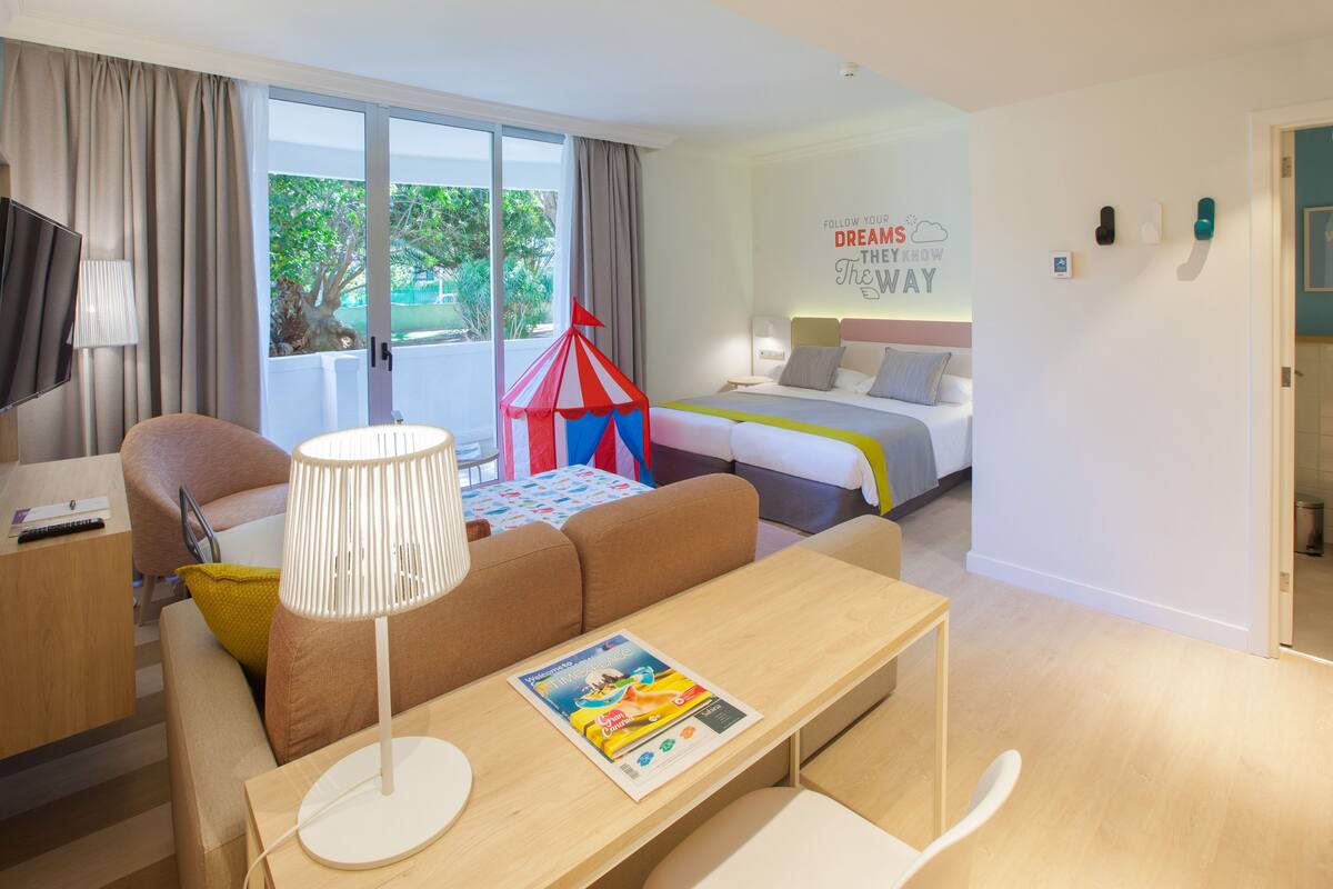 Una habitación de hotel moderna con una cama grande, un sofá, una mesa de comedor y una tienda de juegos.