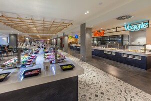 A buffet area with various food stations, including a meat section and a veggie section, in a modern indoor setting.