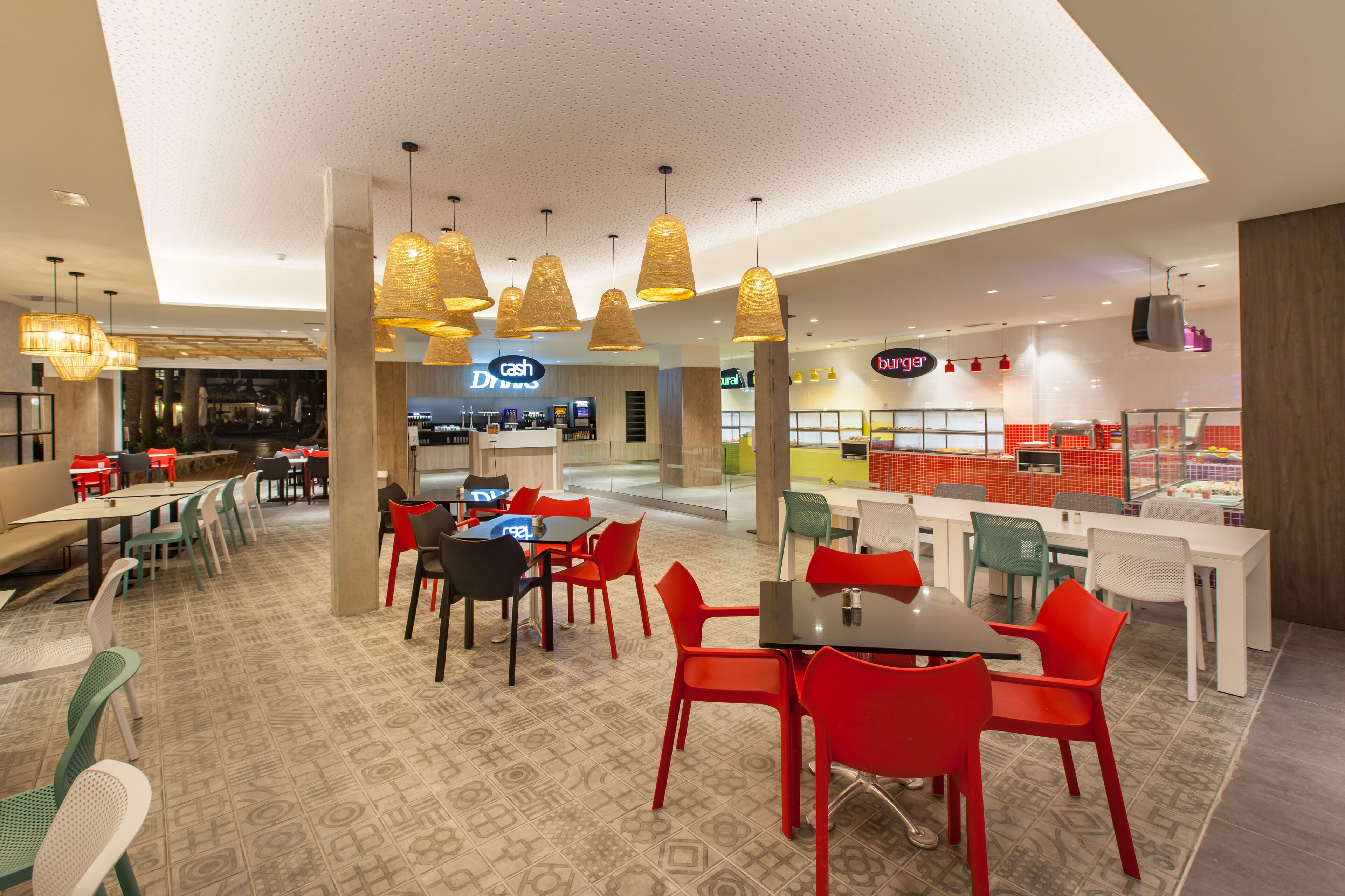 A modern indoor dining area with multiple seating options, including tables and chairs, and a visible counter area in the background.