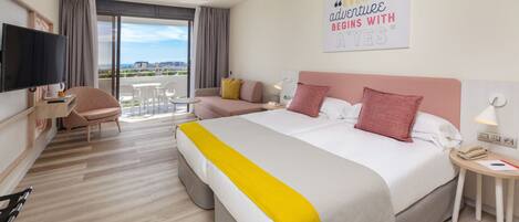 A hotel room with a bed, a desk, a chair, a TV, and a balcony with a view.