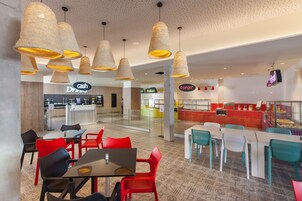 A modern restaurant with red and teal chairs, a cash bar, and a burger counter.