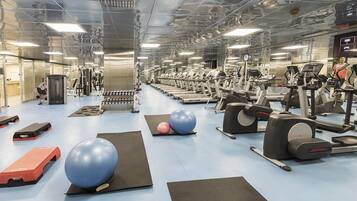 A gym with treadmills, elliptical machines, and exercise balls.