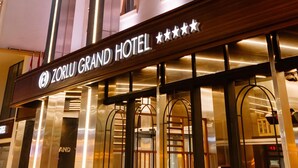 A hotel with a modern facade, multiple windows, and a sign indicating it is the Zorlu Grand Hotel. - Zorlu Grand Hotel Trabzon (Trabzon)
