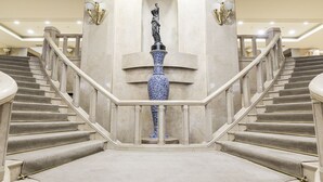 A grand staircase with marble steps and a central blue and white vase sculpture. - Zorlu Grand Hotel Trabzon (Trabzon)