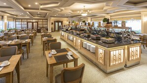 A hotel dining area with multiple tables and chairs, a buffet counter with various food items, and a chandelier. - Zorlu Grand Hotel Trabzon (Trabzon)