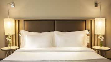 Una habitación de hotel con una cama grande, dos lámparas de noche y un jarrón con flores a cada lado.