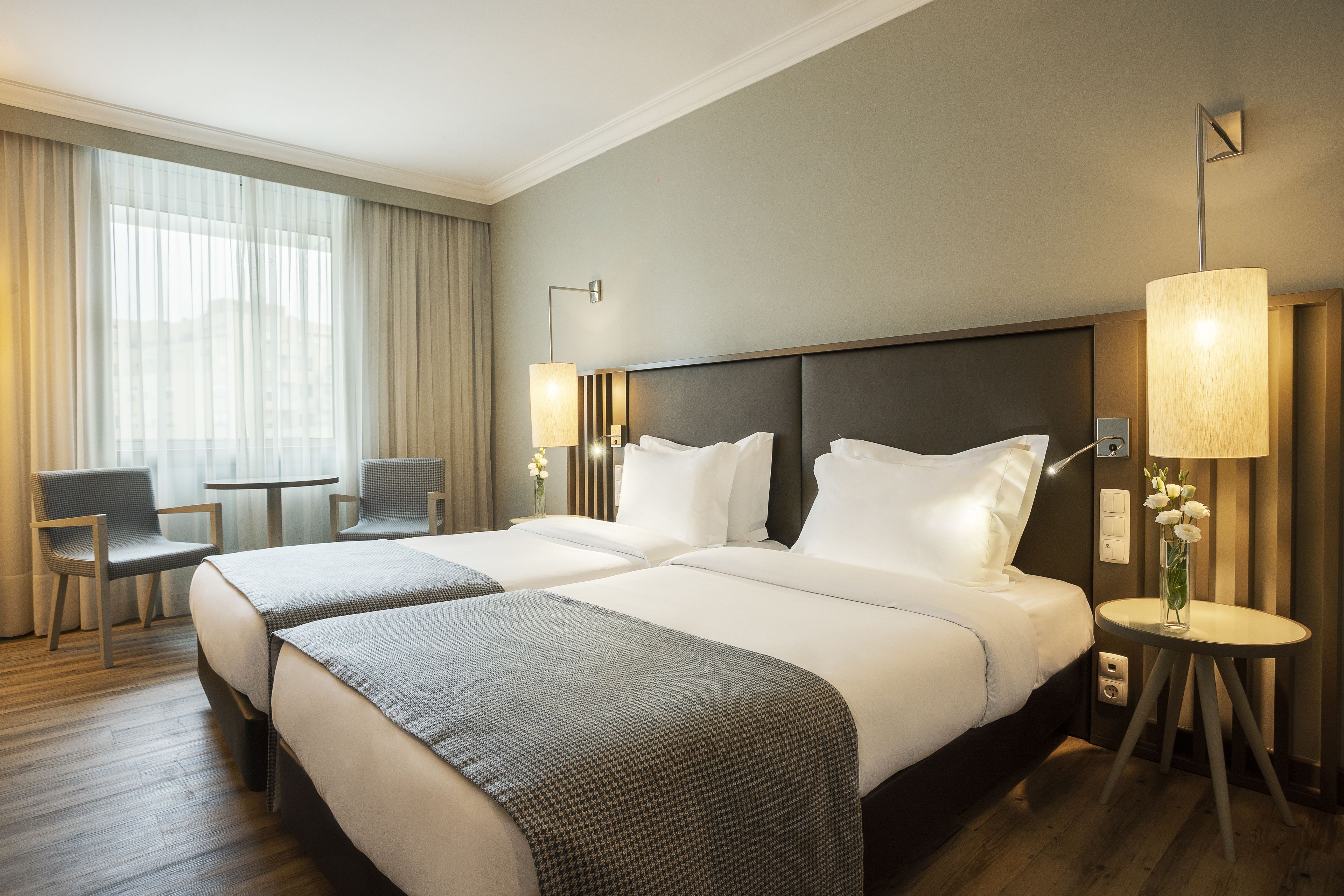 Une chambre d’hôtel avec deux lits, une petite table, une chaise et une lampe.