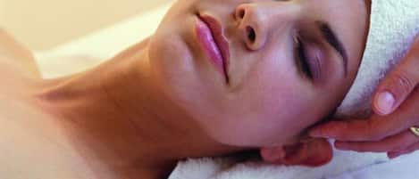 Eine Person liegt auf einem Bett, während eine weiße Handtuch eine Massage gibt.