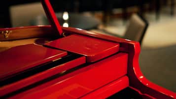 Un piano rouge dans une pièce faiblement éclairée, avec un arrière-plan flou.