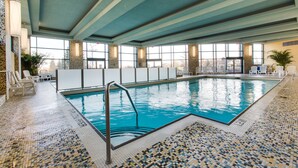 An indoor swimming pool with clear blue water, tiled floor, and a pool ladder. - Brookstreet (Ottawa)