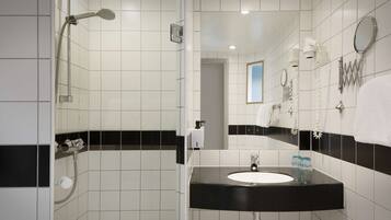 Een moderne badkamer met witte en zwarte tegels, een zwarte wastafel en een douche met een handdouche.