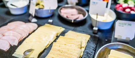 A buffet with various food items including sliced meats, cheeses, and vegetables.