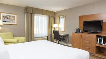 A hotel room with a bed, a desk, a chair, a television, and a framed picture on the wall.