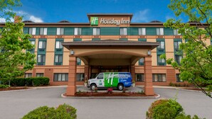 A Holiday Inn Express & Suites building with a van parked in front. - Holiday Inn Manchester Airport by IHG (Manchester)