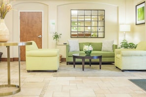 A lobby with a green sofa, a yellow armchair, a round coffee table, and a vase with flowers. - Holiday Inn Manchester Airport by IHG (Manchester)