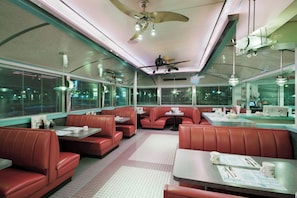 A diner with booths and tables, a ceiling fan, and large windows. - Holiday Inn Manchester Airport by IHG (Manchester)