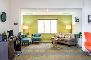 A modern office space with a desk, chairs, a sofa, and a colorful carpet. - Sleep Inn & Suites Harrisonburg near University (Harrisonburg)