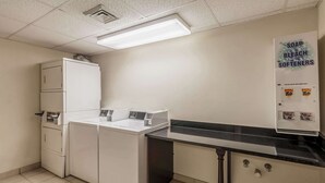Un lavadero equipado con lavadora, secadora y dispensador de jabón, lejía y suavizante, instalado en la pared.
