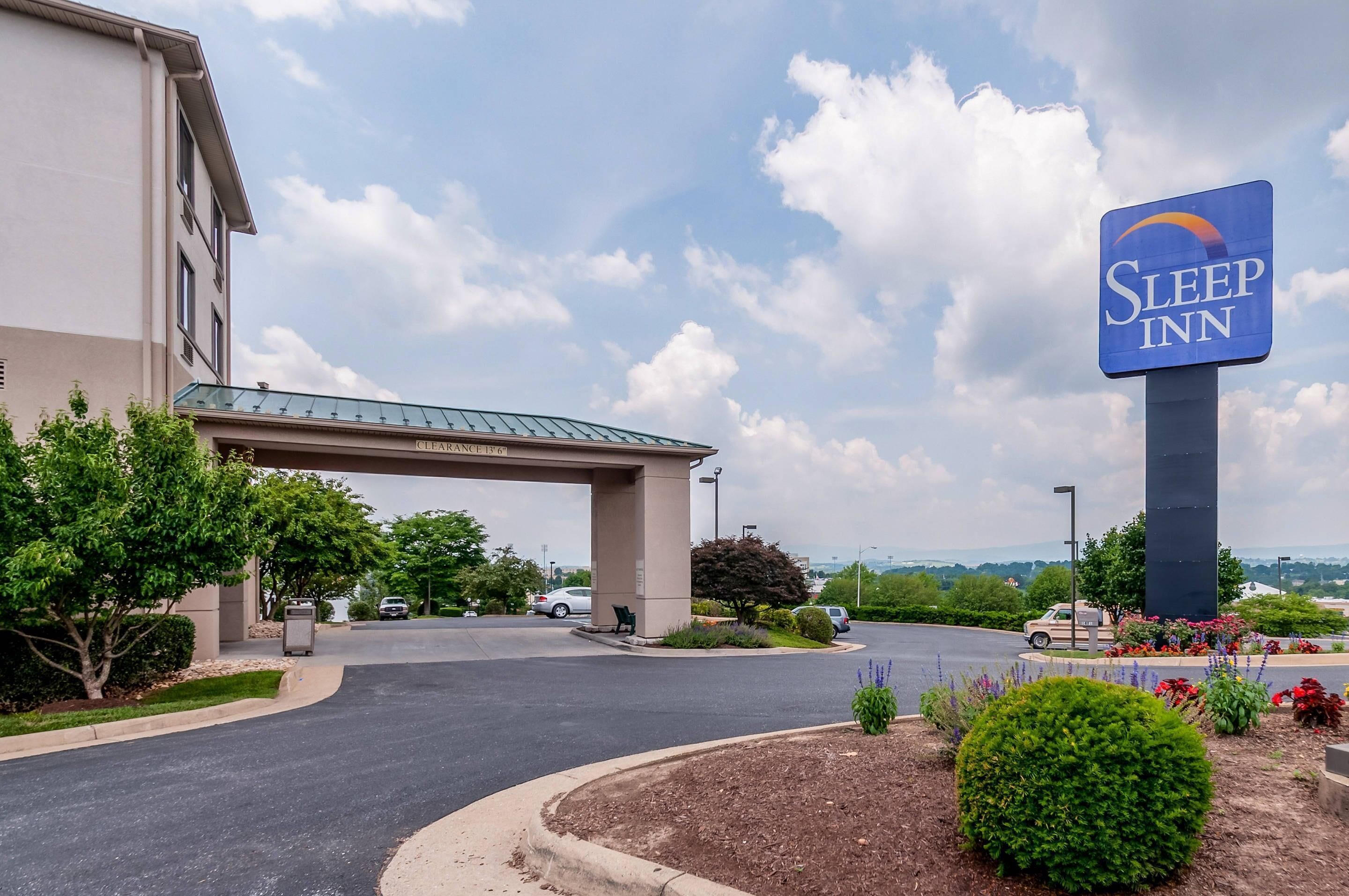 A Sleep Inn hotel with a clear entrance, a covered parking area, and a view of the surrounding landscape.