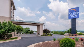 A Sleep Inn hotel with a clear entrance, a covered parking area, and a view of the surrounding landscape.
