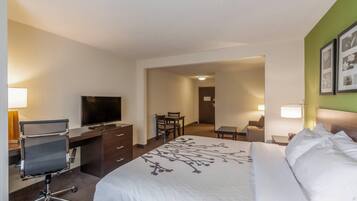 Habitación de hotel con cama, escritorio con silla, televisor y zona de comedor.