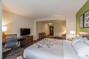 Habitación de hotel con cama, escritorio con silla, televisor y zona de comedor.