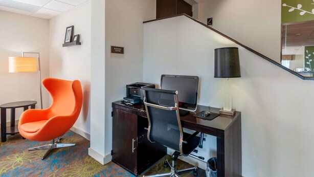 Habitación de hotel con escritorio, dos sillas, una computadora portátil, una impresora y una lámpara.
