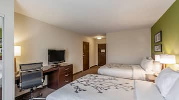 A hotel room with two beds, a desk with a computer, a television, and a door leading to another room.