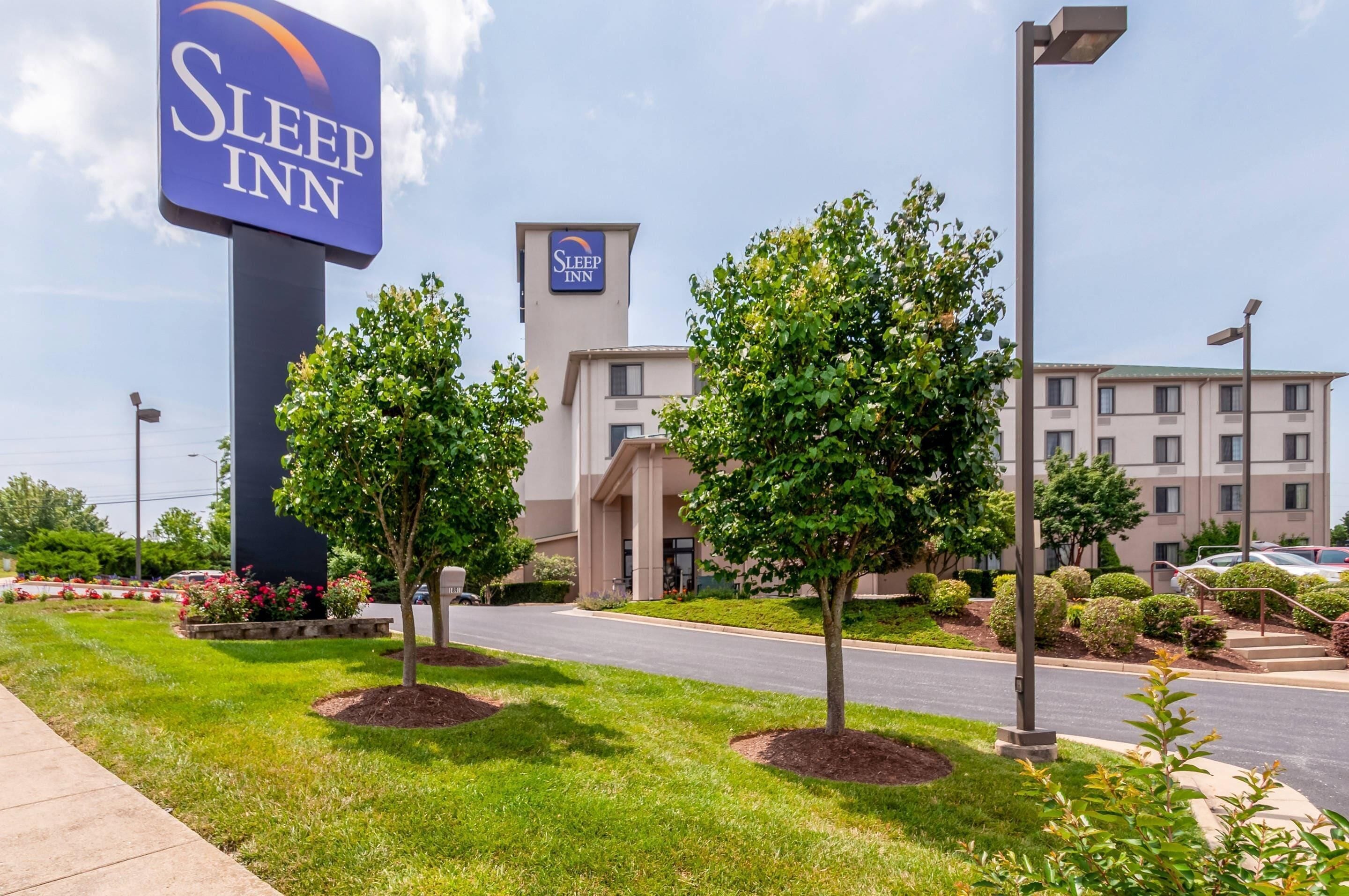 Un hotel Sleep Inn con un letrero llamativo, estacionamiento y un edificio con múltiples ventanas.