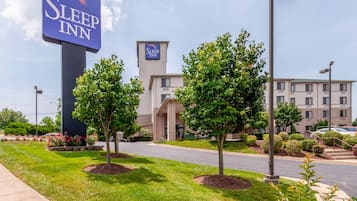 Un hotel Sleep Inn con un letrero llamativo, estacionamiento y un edificio con múltiples ventanas.