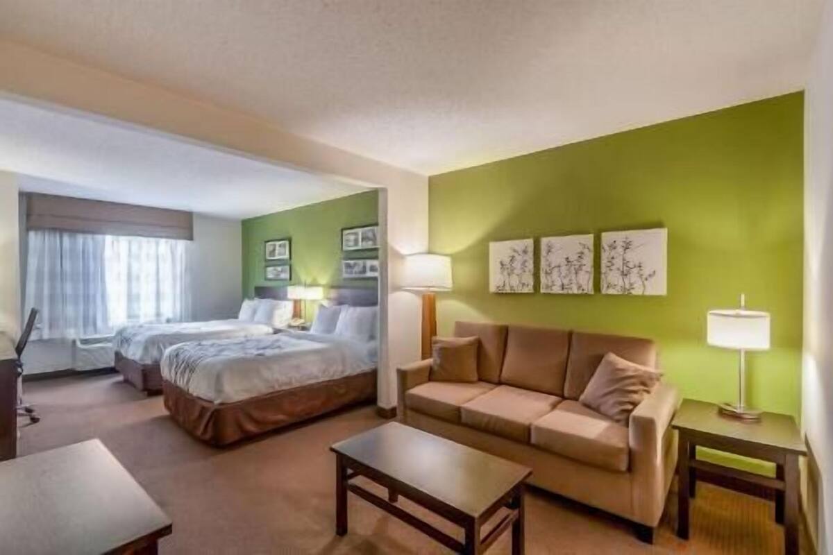 A hotel room with a bed, a sofa, a coffee table, and a lamp.