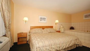 Ein Hotelzimmer mit Bett, Nachttischen, einer Lampe, einem Bild an der Wand und einem gefliesten Badezimmer.