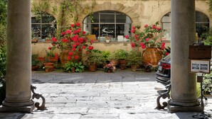 An outdoor courtyard with a stone floor, columns, and potted plants. - Palazzo Niccolini al Duomo (Florence)