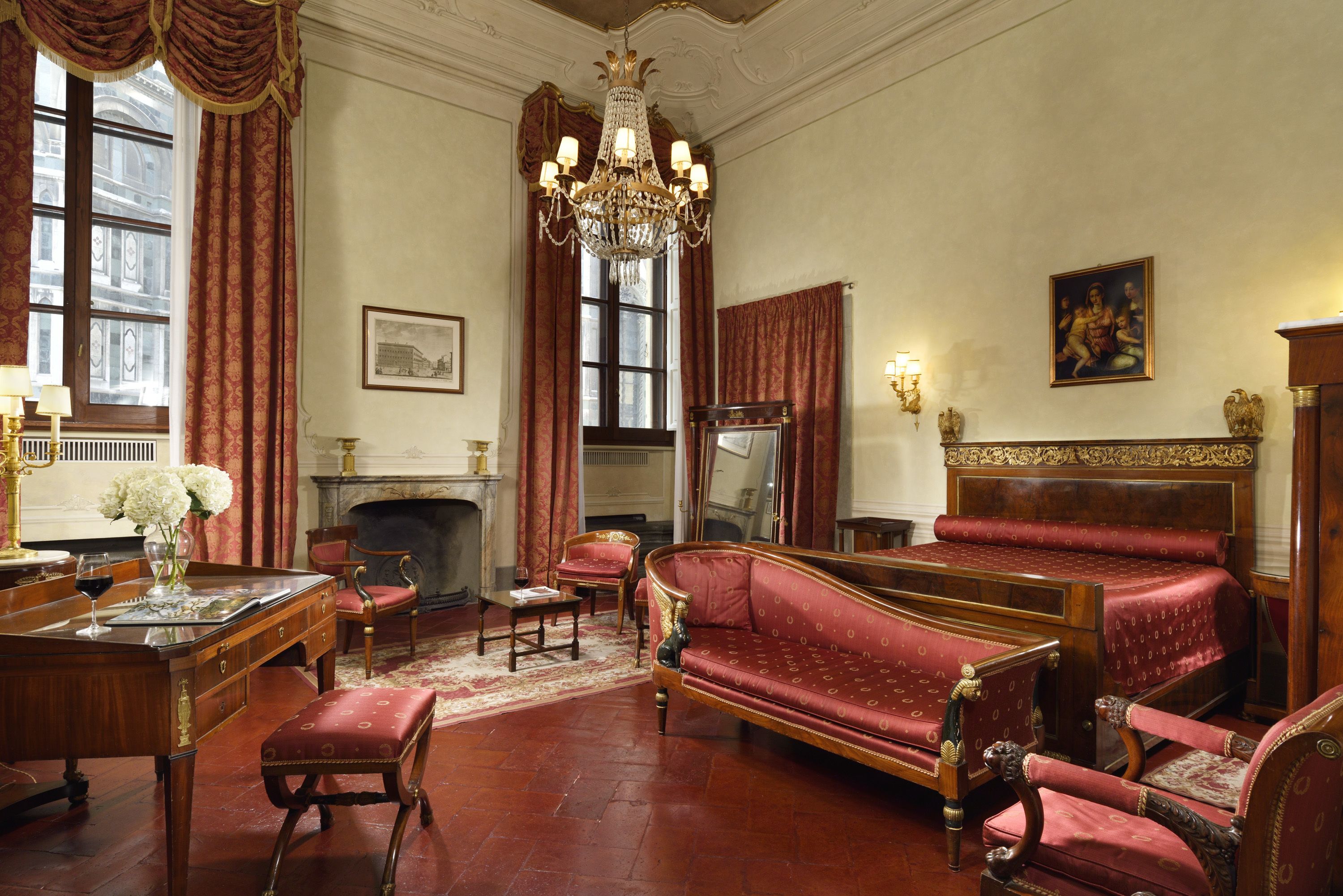 A room with a fireplace, a chandelier, and a sofa.