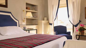 A hotel room with a bed, a chair, a lamp, and a window with curtains.
