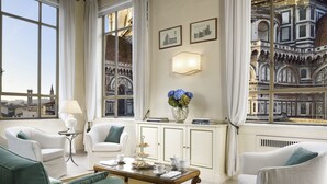 A room with a view of a historic building, white furniture, a table with a vase of flowers, and a lamp. - Palazzo Niccolini al Duomo (Florence)