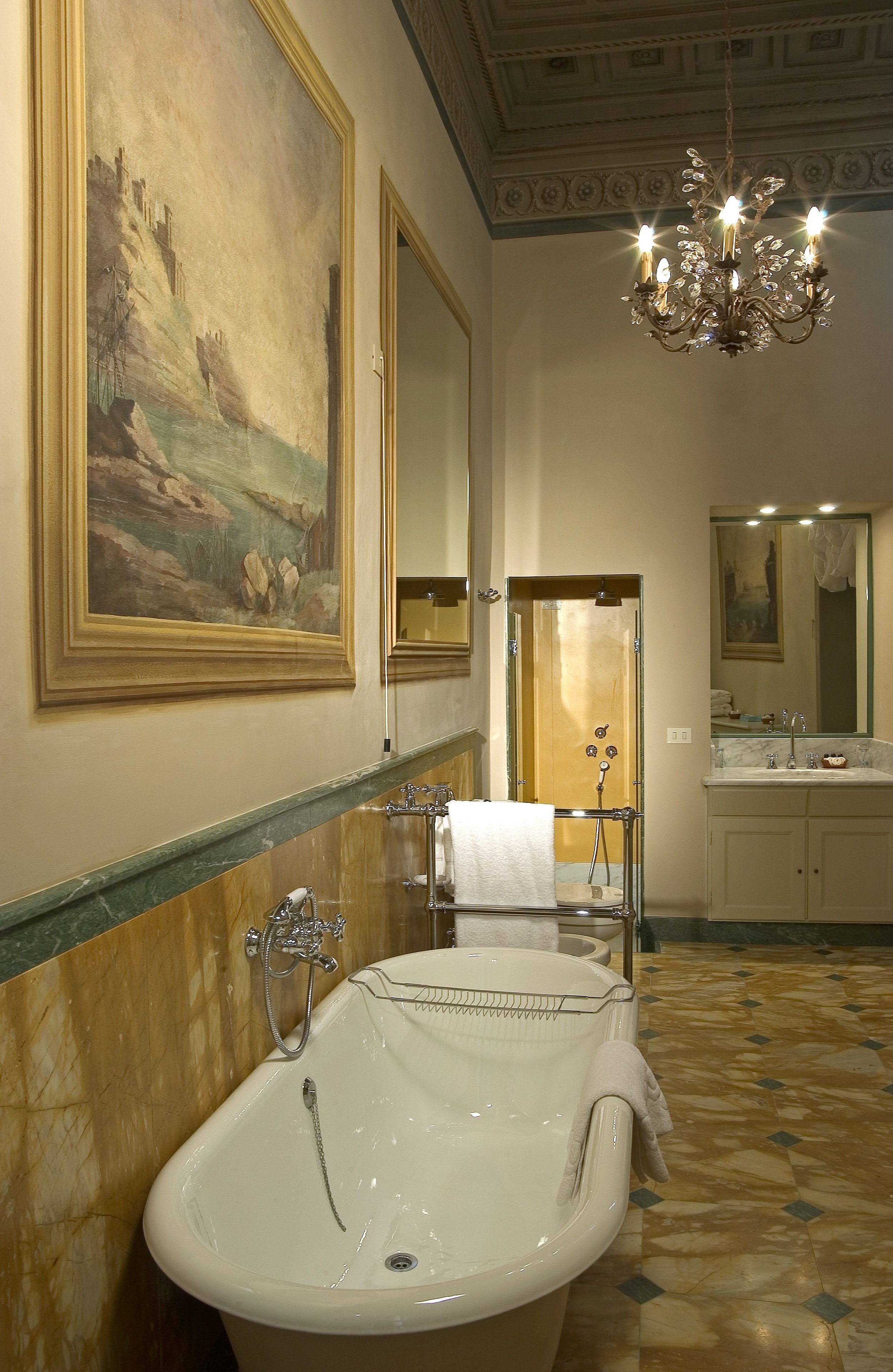 A bathroom with a freestanding bathtub, a large mirror, and a chandelier.